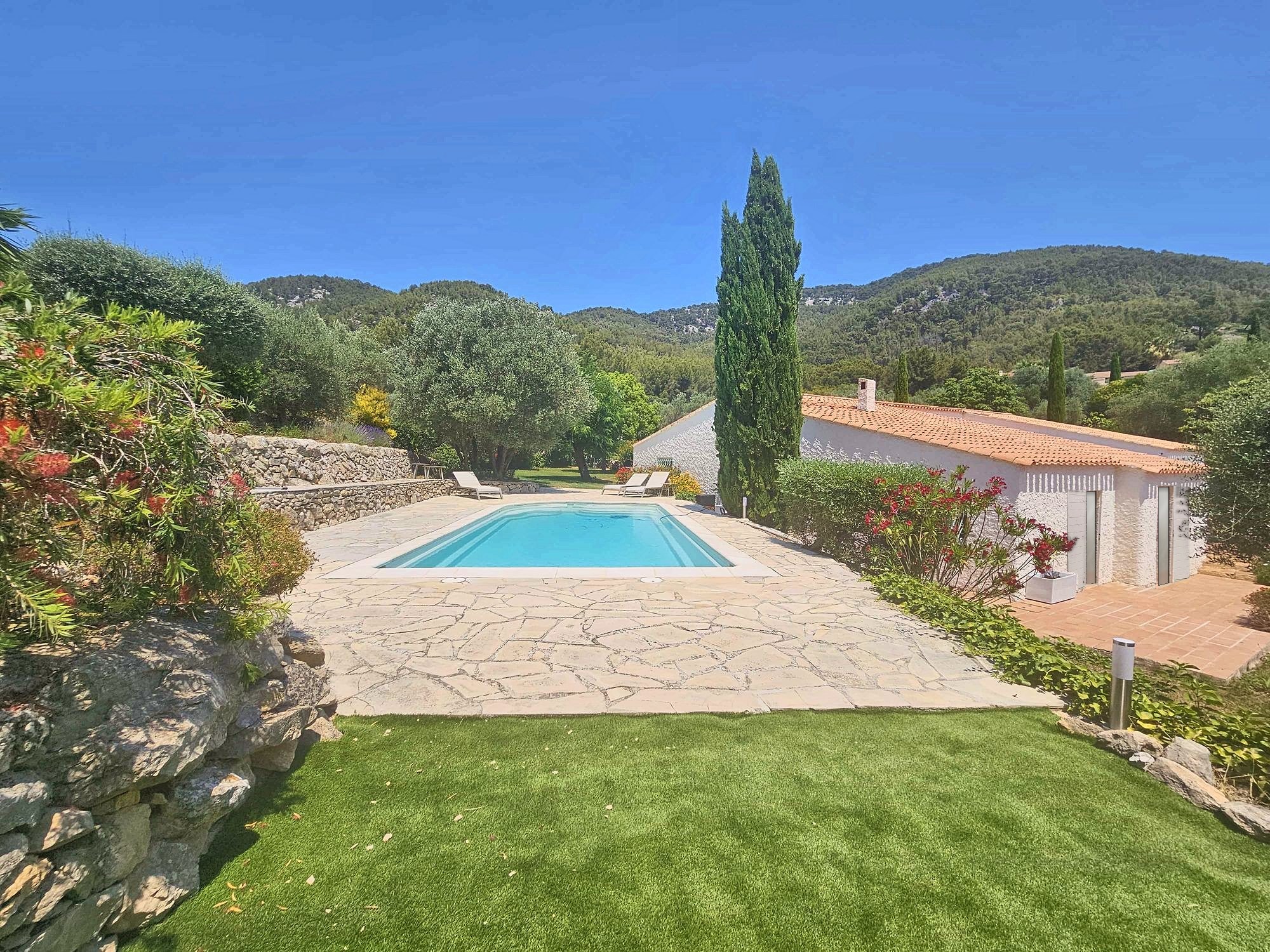 La piscine chauffée, sa plage en pierre et les cyprès